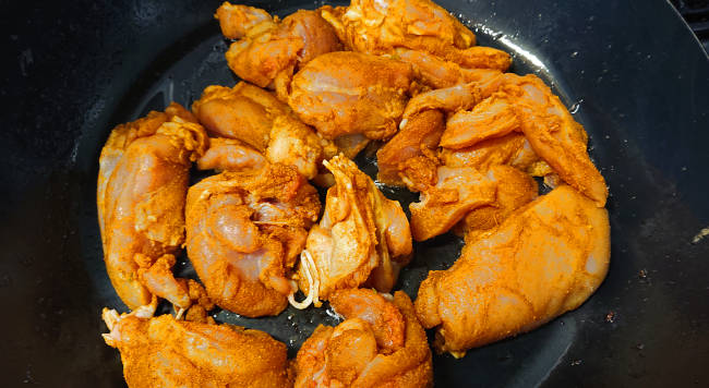 スパイスを揉み込んだ鶏もも肉を炒める